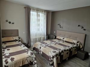 a bedroom with two beds and a window at Le Faubourg in Figeac