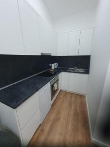 a kitchen with white cabinets and a black counter top at MB Apartman in Čapljina