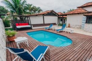 a deck with a pool and chairs and a table at Pousada Maria Maria Búzios in Búzios