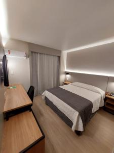 a hotel room with a bed and a desk at Mogano Business Hotel- ELETROPOSTO in Chapecó