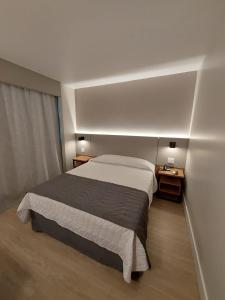 ein Schlafzimmer mit einem großen Bett und zwei Nachttischen in der Unterkunft Mogano Business Hotel- ELETROPOSTO in Chapecó