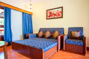 a bedroom with a bed and a chair at 'Golden Sea Breeze' Beach villa in Benaulim