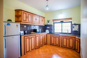 a kitchen with wooden cabinets and a white refrigerator at 'Golden Sea Breeze' Beach villa in Benaulim
