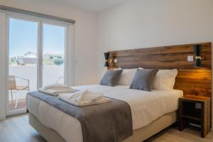 una camera con un grande letto con testiera in legno di Casa Dona Maria a Montargil