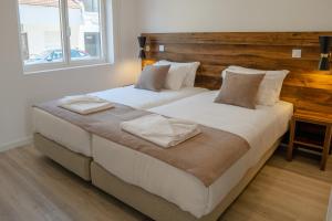 two beds in a bedroom with a wooden headboard at Casa Dona Maria in Montargil