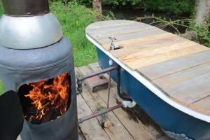 a woodburning stove next to a boat and a table at Caban Delor. Off-grid glamping experience. Walking distance into Caernarfon. 20-min drive to Snowdonia or Anglesey. in Caernarfon
