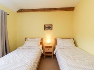 two twin beds in a room with a lamp on a table at Little Barn in Chippenham