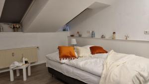 Beauty and Beast 24h-Check-in, 6 Pers, Klima, Massageliege في Cremlingen: غرفة نوم مع سرير مع وسائد برتقالية وبيضاء