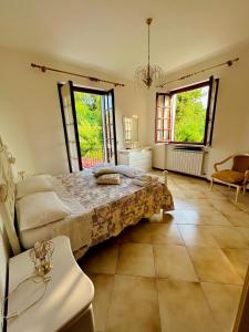 a bedroom with a bed and a table and two windows at La casa del Tiglio in Sarzana