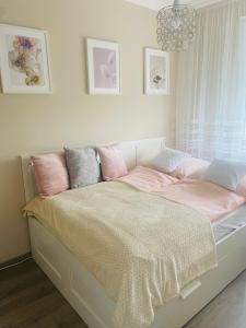 a bed with pink and grey pillows on it at Sóstó Forest Apartman in Nyíregyháza