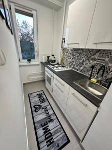 a kitchen with white cabinets and a sink and a window at Sóstó Forest Apartman in Nyíregyháza