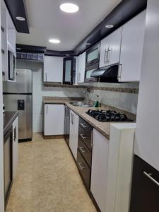 a large kitchen with white cabinets and appliances at Hospedaje Casa Leví in Cali