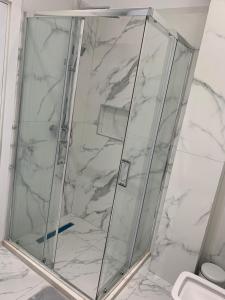 La salle de bains en marbre blanc est pourvue d'une douche. dans l'établissement You are only one booking away, à Kamëz