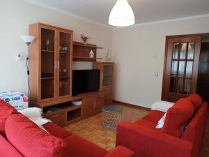 een woonkamer met twee rode banken en een tv bij Altamar in Llanes