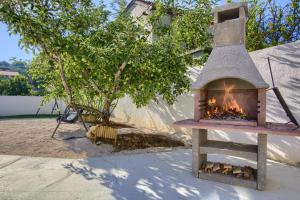 un horno de leña en un patio con un árbol en Apartments Villa Mihaela, en Banj