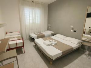 - une chambre avec 2 lits, une table et un miroir dans l'établissement SOMA, à Rimini
