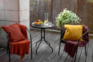 2 sillas y una mesa con un bol de fruta en AA Apartament, en Varsovia