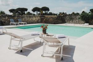 a pool with a white table and chairs next to a pool at Masseria Paralupi in Lecce