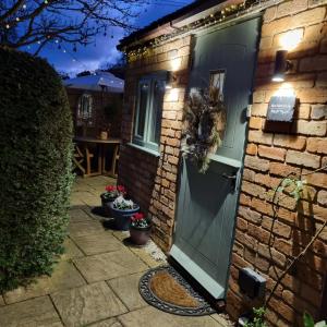 a brick house with a green door and a patio at Bijou Malthouse in Alcester