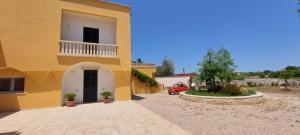 a yellow building with a balcony and a car in a driveway at Villa PARADISO - Tra Ulivi e Tramonti da Cartolina in Muro Leccese