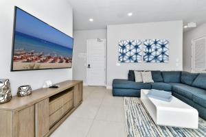 uma sala de estar com um sofá azul e uma televisão em Stylish Condo near Disney w Hotel Amenities 7770- 26-110 em Kissimmee