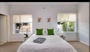 um quarto branco com uma cama grande e almofadas verdes em East Prestige lodge em Joanesburgo