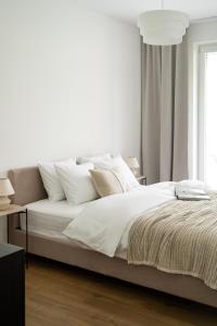 Unique & Modern Apartment Zabłocie في كراكوف: غرفة نوم بيضاء مع سرير مع شراشف ووسائد بيضاء