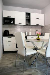 een keuken met witte kasten en een tafel en stoelen bij Apartment Bruna in Solin