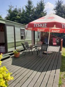 eine Holzterrasse mit einem Tisch und einem Sonnenschirm in der Unterkunft Domek Holenderski in Mikołajki
