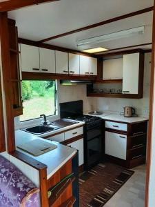 a kitchen with white cabinets and a sink in an rv at Domek Holenderski in Mikołajki