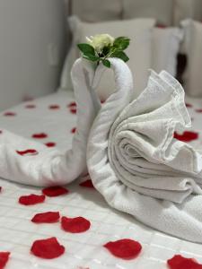 two swans towels on a bed with red rose pedals at Pousada Capital das Águas in Maceió