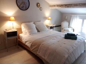 1 dormitorio con 1 cama blanca grande y reloj en la pared en La maison perchée, en Aigues-Mortes