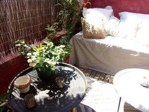un patio con una mesa con flores y un sofá en La maison perchée, en Aigues-Mortes