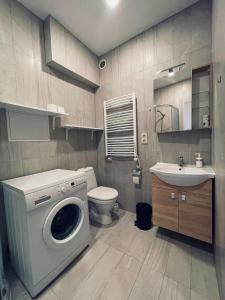 ein Badezimmer mit einer Waschmaschine und einem Waschbecken in der Unterkunft SKY Apartments in Kaunas