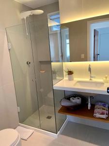 a bathroom with a glass shower and a sink at Apartamento vista do mar, pé na areia e águas tranquilas, no cento de Guarapari in Guarapari