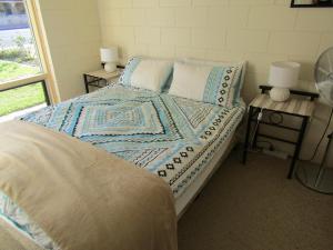 a bedroom with a bed with a blue and white quilt at Little Ray of Sunshines by the Sea in Edithburgh