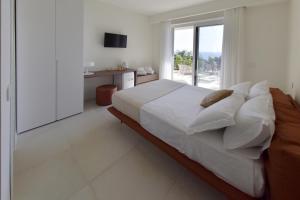 una camera bianca con un grande letto e una finestra di Relais Ulivo Ariana a Gaeta
