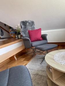 a living room with two chairs and a red pillow at Jensen-Huus in Dagebüll