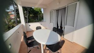 a white table and chairs in a room with a window at Apartments Dado in Novalja