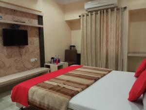 a bedroom with a bed and a tv on the wall at Pachmarhi Shri Krishna Hotel in Pachmarhī