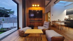 uma sala de estar com um sofá, uma mesa e uma televisão em The Cedarwoods - luxury for up to 5 and your woof! em Christchurch