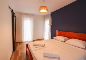 1 dormitorio con 1 cama blanca grande y pared azul en Cottages in Kaprovani "Family nest" en Ureki