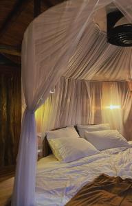 1 dormitorio con cama con dosel, sábanas y almohadas blancas en Kairos Deluxe, en Melgar