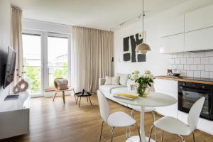 biała kuchnia i salon ze stołem i krzesłami w obiekcie Unique & Modern Apartment Zabłocie w Krakowie