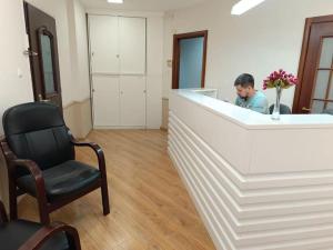 un homme dans une salle d'attente avec une chaise dans l'établissement Coral guest house Netanya, à Netanya