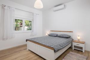 ein weißes Schlafzimmer mit einem Bett und zwei Fenstern in der Unterkunft Apartment Div in Lovran