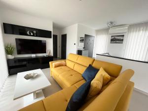 a living room with a yellow couch and a table at Napfény Terasz Apartman in Vonyarcvashegy