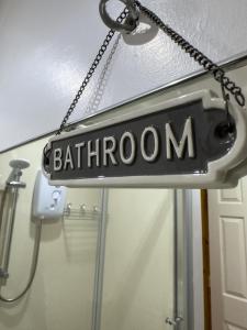 a sign that reads bathroom hanging from a ceiling at Clare Forest Apartment in Ballycastle