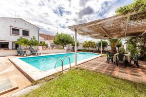 a pool with a table and chairs next to a house at Casa Rural con piscina- Tierra de Barros 