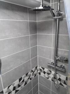 y baño con ducha y azulejos blancos y negros. en Studio Ventadour, en Égletons